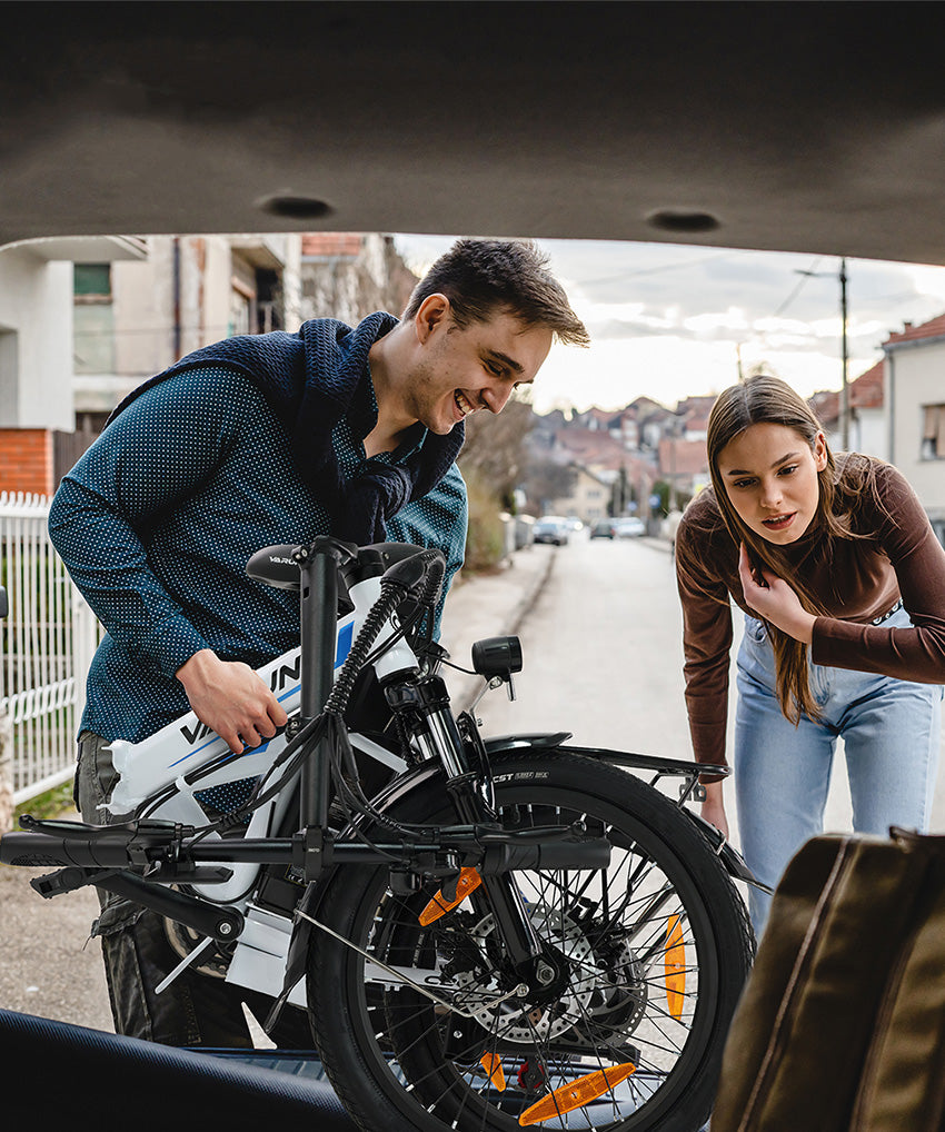 The couple is folding the bike and put it into the truck