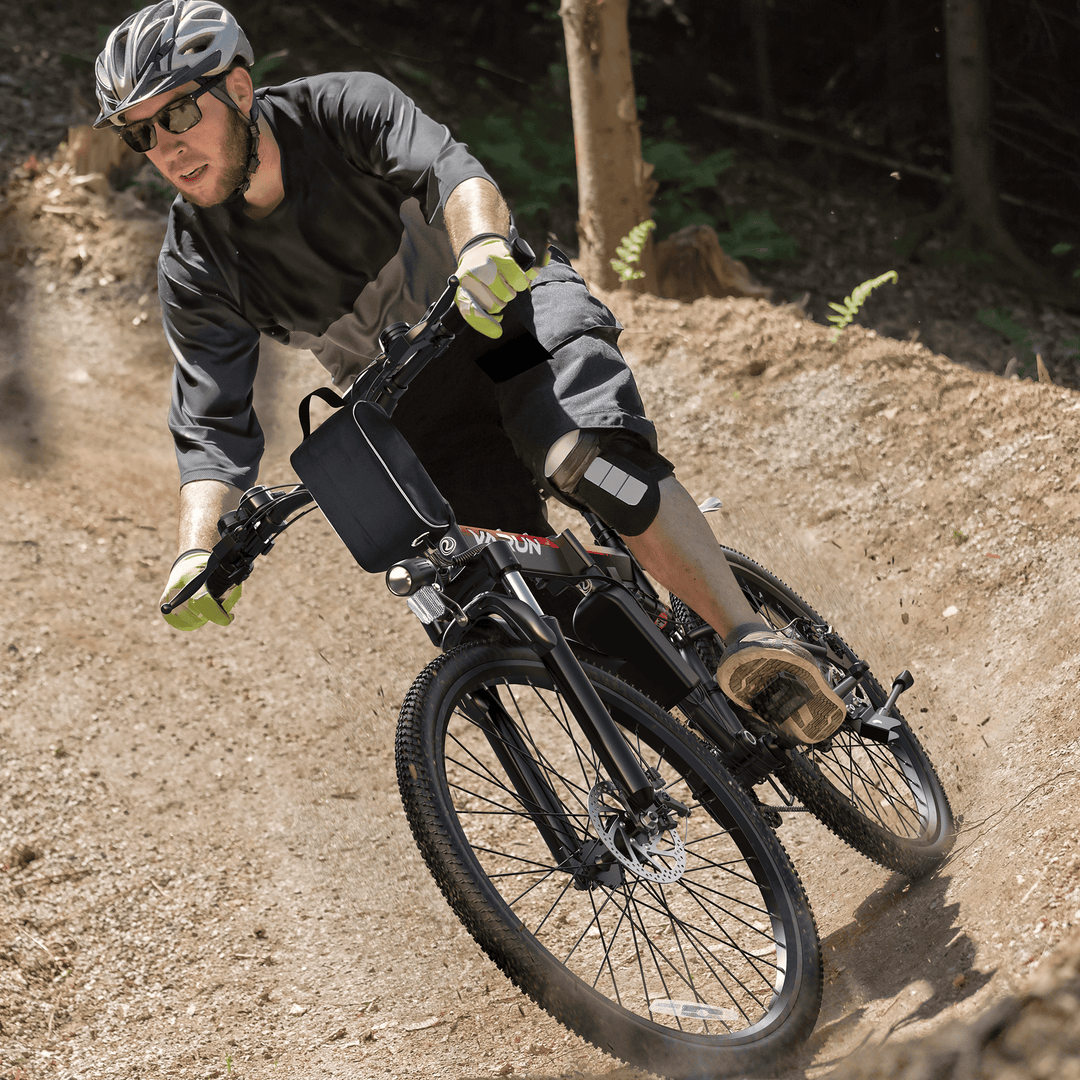 Male cyclist riding a black varun electric mountain bike on an off-road dirt path, equipped with safety gear (helmet, gloves, knee pads) – ideal for outdoor adventure and e-bike enthusiasts.